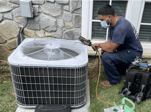 HVAC technician using professional testing equipment while servicing an outdoor residential air conditioning condenser